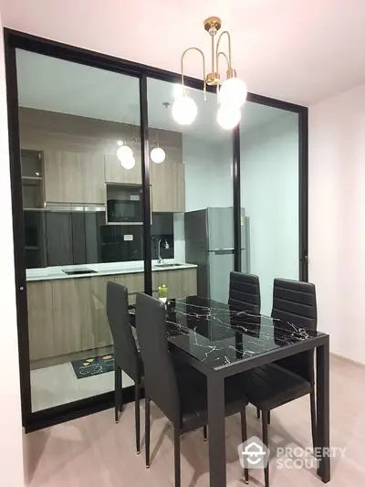 Modern dining area with sleek black marble table and glass partition to stylish kitchen.