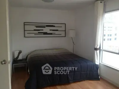 Cozy bedroom with modern decor and large window for natural light.