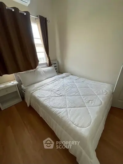 Cozy bedroom with wooden flooring and natural light, perfect for relaxation.