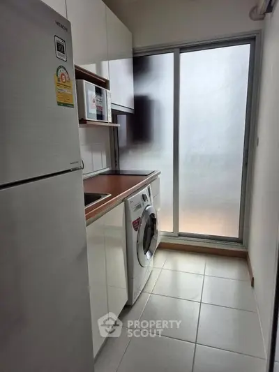 Modern kitchen with washing machine and fridge in compact layout