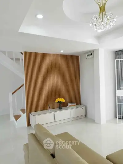 Modern living room with elegant decor and stylish lighting, featuring a cozy seating area and decorative wall panel.