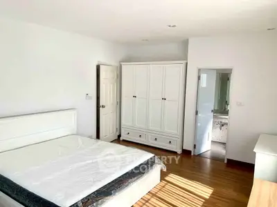 Spacious bedroom with wooden flooring and ample natural light