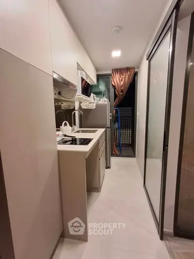 Modern compact kitchen with sleek design and balcony access in urban apartment