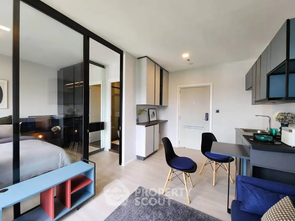 Modern open-plan living room with sleek furniture and glass partition to bedroom