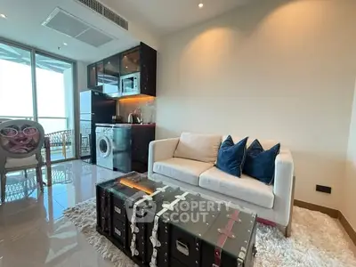 Modern living room with unique trunk coffee table and compact kitchen area.