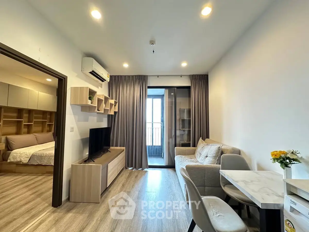 Modern living room with open layout, cozy furniture, and balcony access in stylish apartment.