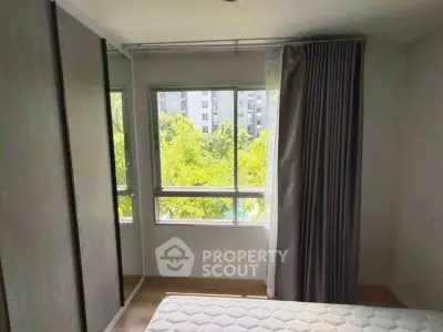 Bright bedroom with large window and lush green view, featuring a comfortable mattress and modern wardrobe.