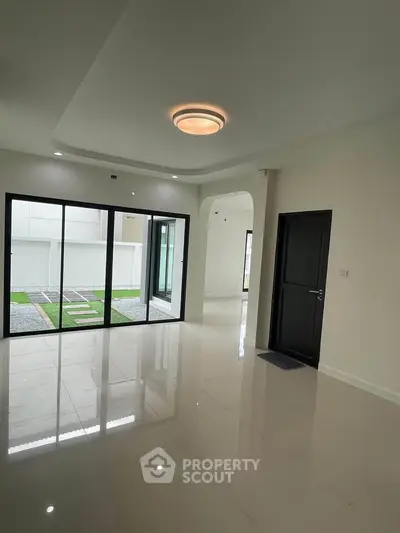 Spacious modern living room with large glass doors opening to a serene garden view.