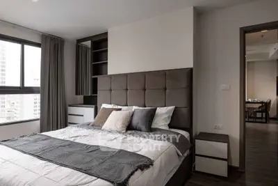 Modern bedroom with stylish decor and city view, featuring a cozy bed and elegant furnishings.