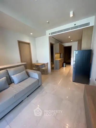 Modern living room with sleek furniture and open kitchen layout in a stylish apartment.