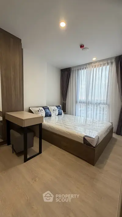 Modern bedroom with large window and stylish furnishings in a contemporary apartment.