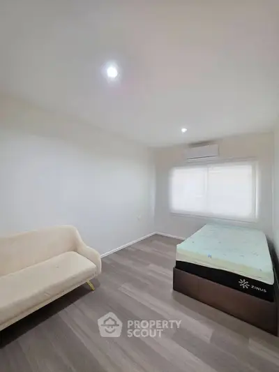 Spacious bedroom with minimalist decor, featuring a cozy bed and elegant flooring, perfect for relaxation.