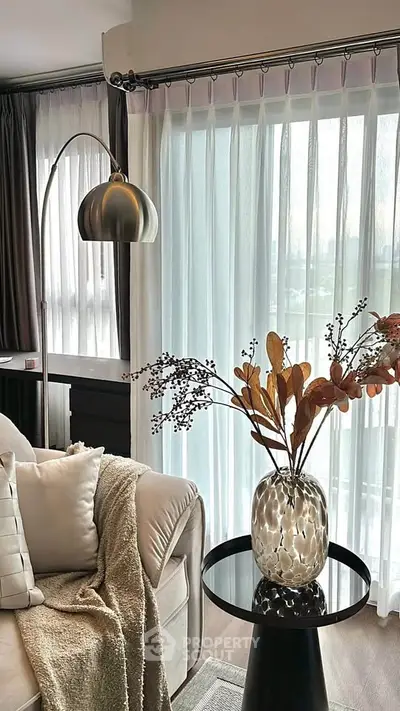 Stylish living room with modern decor and large window, featuring cozy seating and elegant lighting.