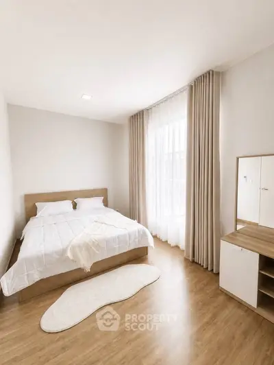 Modern minimalist bedroom with wooden flooring and natural light