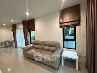 Spacious living room with modern leather sofa and elegant curtains in a bright, airy setting.