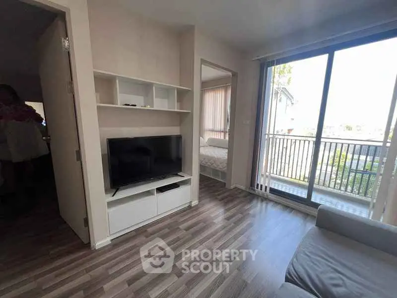 Modern living room with sleek flooring and balcony view in a cozy apartment.