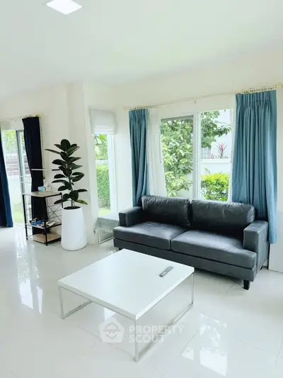 Bright and modern living room with sleek sofa and large windows.