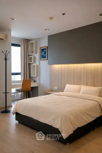 Modern bedroom with stylish decor and natural light, featuring a cozy bed and workspace.