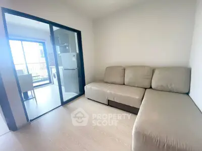 Modern living room with sliding glass doors leading to a bright balcony and kitchen area.