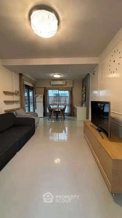 Spacious living room with modern decor and dining area, featuring a sleek TV setup.