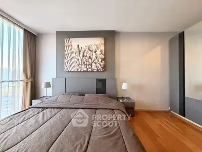 Modern bedroom with cityscape artwork and wooden flooring in a stylish apartment.