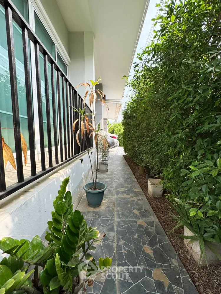 Charming garden pathway with lush greenery and potted plants leading to a serene entrance.