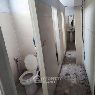 Spacious shared bathroom with multiple stalls and modern fixtures in a commercial building.