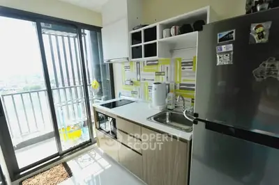 Modern kitchen with balcony view, featuring sleek cabinetry and stainless steel appliances.