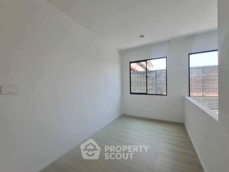 Bright empty room with large windows and wooden flooring