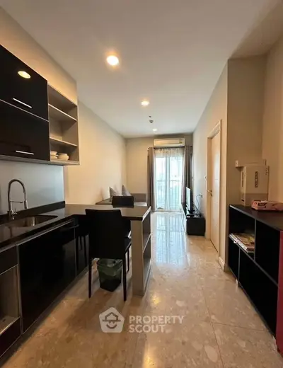 Modern apartment with sleek kitchen and cozy living area, featuring elegant lighting and a compact design.
