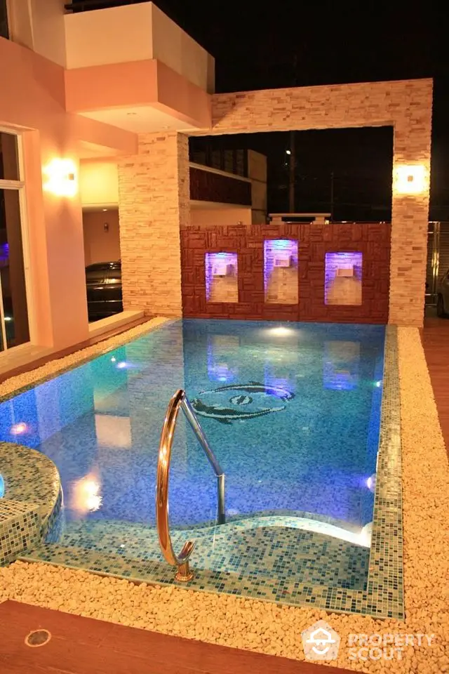 Luxurious modern home with illuminated private pool and elegant stone accents.