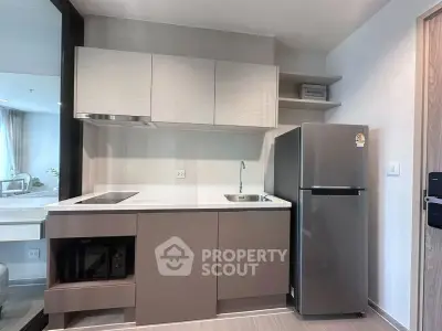 Modern compact kitchen with sleek cabinetry and stainless steel fridge in a stylish apartment.