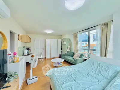 Bright and airy studio apartment with modern furnishings and large windows offering natural light.