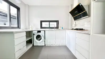 Modern kitchen with sleek white cabinets and built-in washing machine