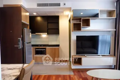 Modern open-plan living room with sleek kitchen and stylish TV unit, featuring wood accents and contemporary design.