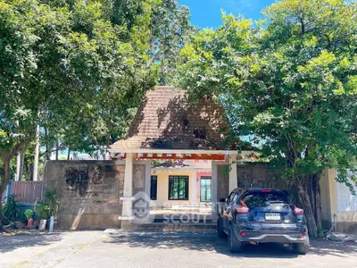 Charming property entrance with lush greenery and spacious driveway