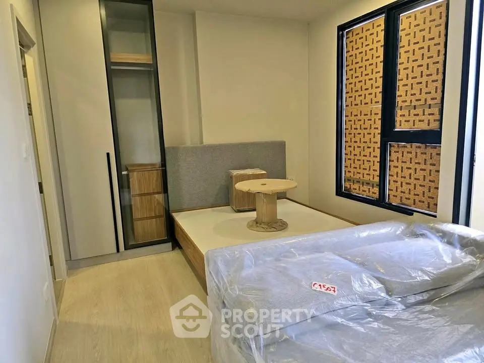 Modern bedroom with stylish furniture and large window, perfect for urban living.
