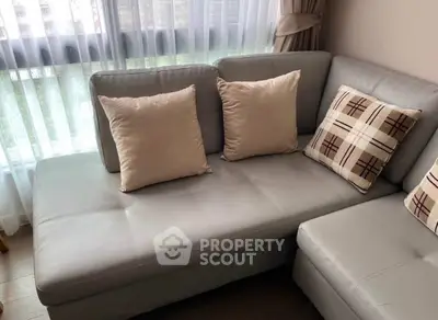 Cozy living room with modern gray sectional sofa and stylish plaid cushions by a sunlit window.