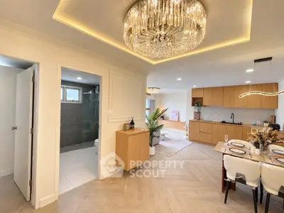 Luxurious open-plan living room with elegant chandelier and modern kitchen design.