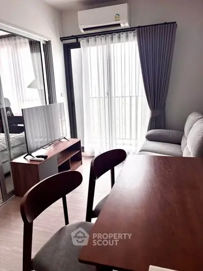 Modern living room with sleek furniture and natural light, featuring a cozy sofa and stylish dining area.