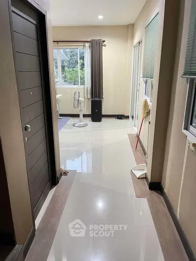Spacious hallway with glossy tiles and natural light, leading to a cozy living area.