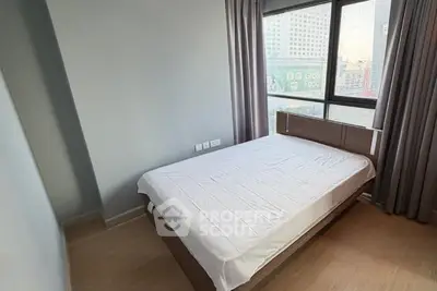 Modern bedroom with large window and city view, featuring a comfortable bed and minimalist decor.