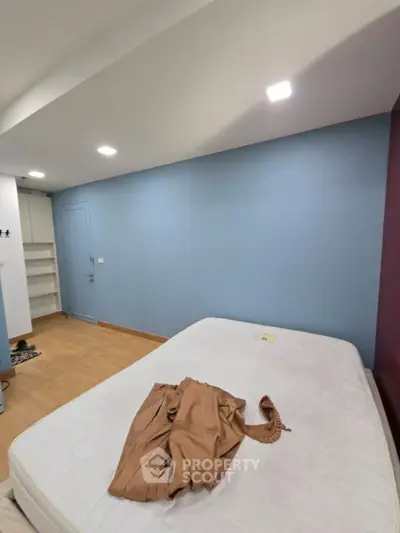 Spacious bedroom with blue accent wall and wooden flooring