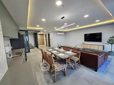 Spacious modern living room with open kitchen and elegant dining area, featuring sleek furniture and ambient lighting.