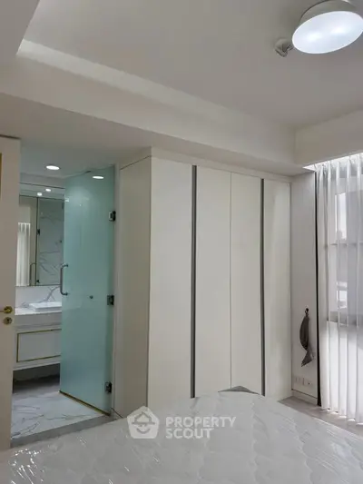 Modern bedroom with ensuite bathroom and large window for natural light.