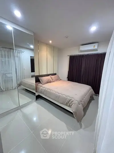 Modern bedroom with sleek design, mirrored wardrobe, and cozy bedding in a stylish apartment.