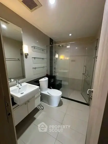 Modern bathroom with glass shower and sleek fixtures in a contemporary apartment.