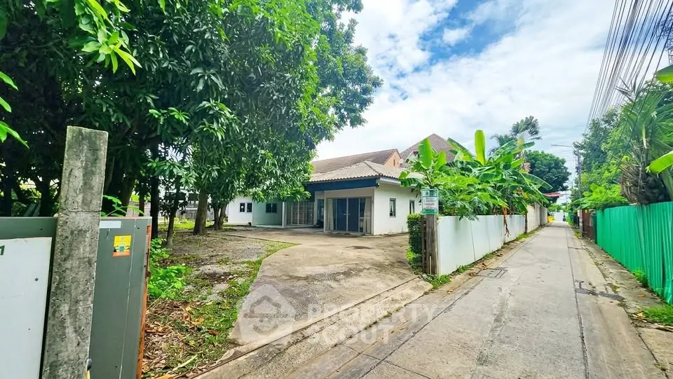 Charming single-story house with lush greenery and spacious driveway in a serene neighborhood.
