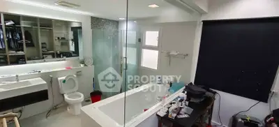 Modern bathroom with glass shower, bathtub, and sleek fixtures in a stylish home.