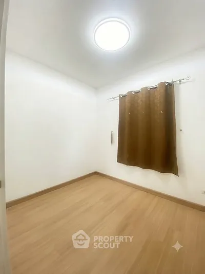 Minimalist empty room with wooden flooring and curtain, ideal for customization.
